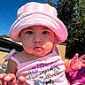 Camila is registered to the contest to win money with this photo: baby, child, pink_hat, pink_clothing, outdoor, blue_sky, trees, sunlight, cute, face, chubby_cheeks, tank_top, cartoon_print, hand, person, summer, nature, portrait, expression, curious