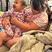 Camila joined the competition — help win amazing prizes! child, baby, sibling, couch, blanket, smiling, happy, indoor, family, clothing, pajamas, person, home, living_room, hug, cute, toddler, girl, infant, comfort
