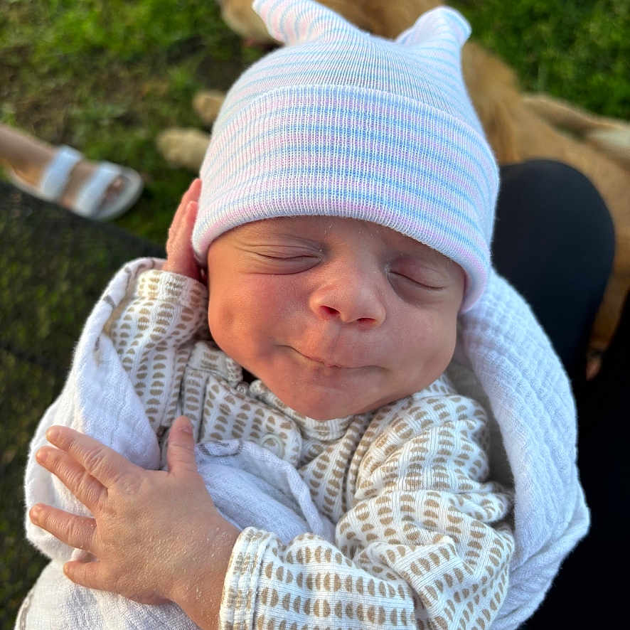 William joined the competition — help win amazing prizes! animal, baby, blanket, clothing, cozy, cute, dog, face, grass, hand, hat, headwear, infant, nature, newborn, outdoor, person, pet, resting, sleeping