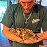 affection, baby_dogs, beard, casual_clothing, cute, door, gentle, green_shirt, hands, holding, indoor, man, necklace, pet, puppies, sleeping, small_animals, tattoo, window, wood_floor
