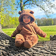 Athéna a rejoint le concours — aidez-le/la à gagner de superbes lots ! baby, bear_costume, blue_sky, child, costume, cute, daylight, face, greenery, happy, hooded, infant, nature, outdoor, plush, portrait, sitting, smiling, sunny, tree_trunk