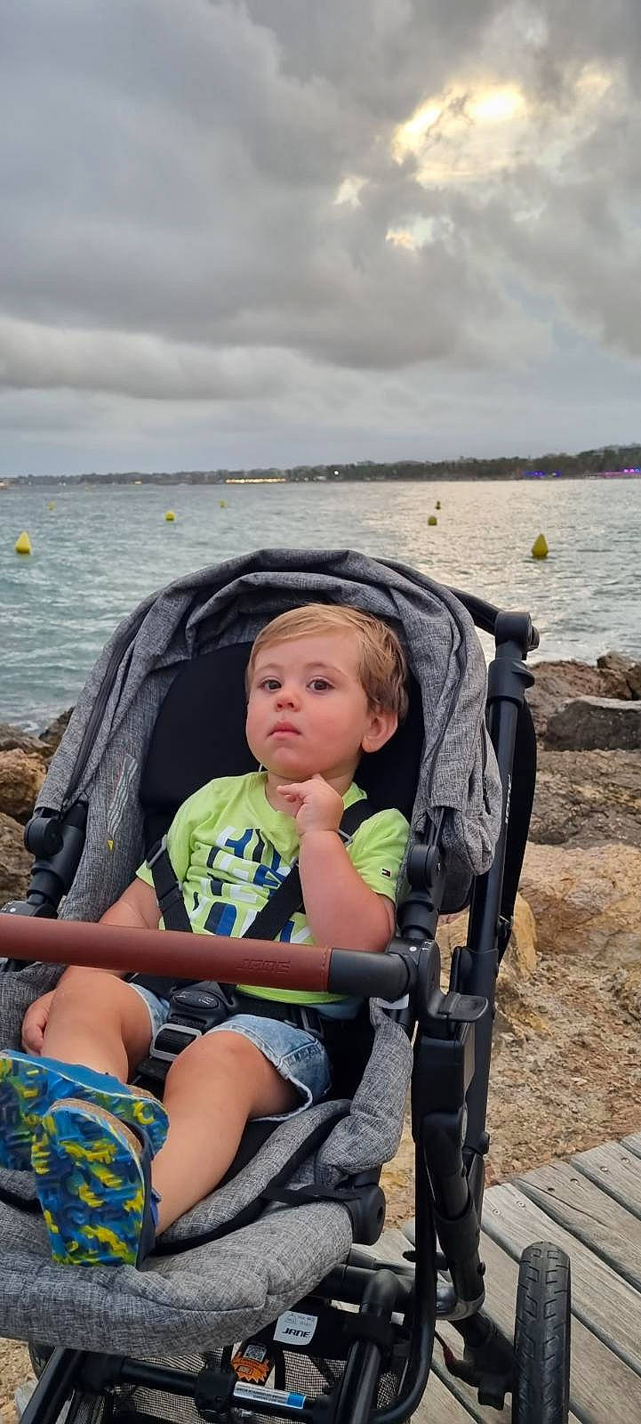 Ishaq a rejoint le concours — aidez-le/la à gagner de superbes lots ! baby_carriage, beach, chair, child, cloud, fun, human, lake, leisure, mammal, person, personal_protective_equipment, recreation, sand, shorts, sitting, sky, toddler, travel, vertebrate