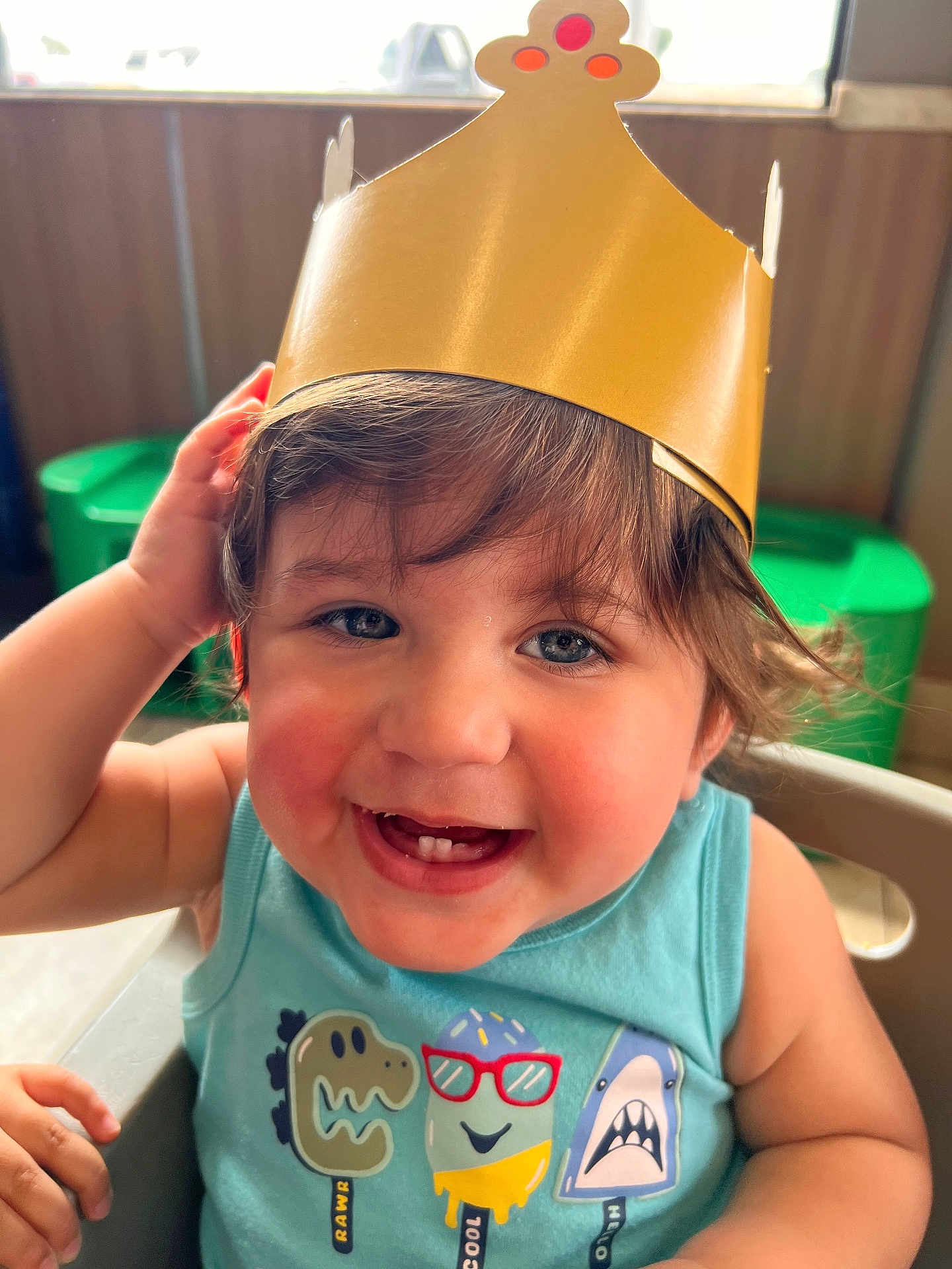 Benjamin joined the competition — help win amazing prizes! toddler, child, smiling, crown, paper_crown, tank_top, cartoon, popsicle, high_chair, indoor, happy, cute, short_hair, blue_shirt, teeth, face, person, sitting, playful, bright