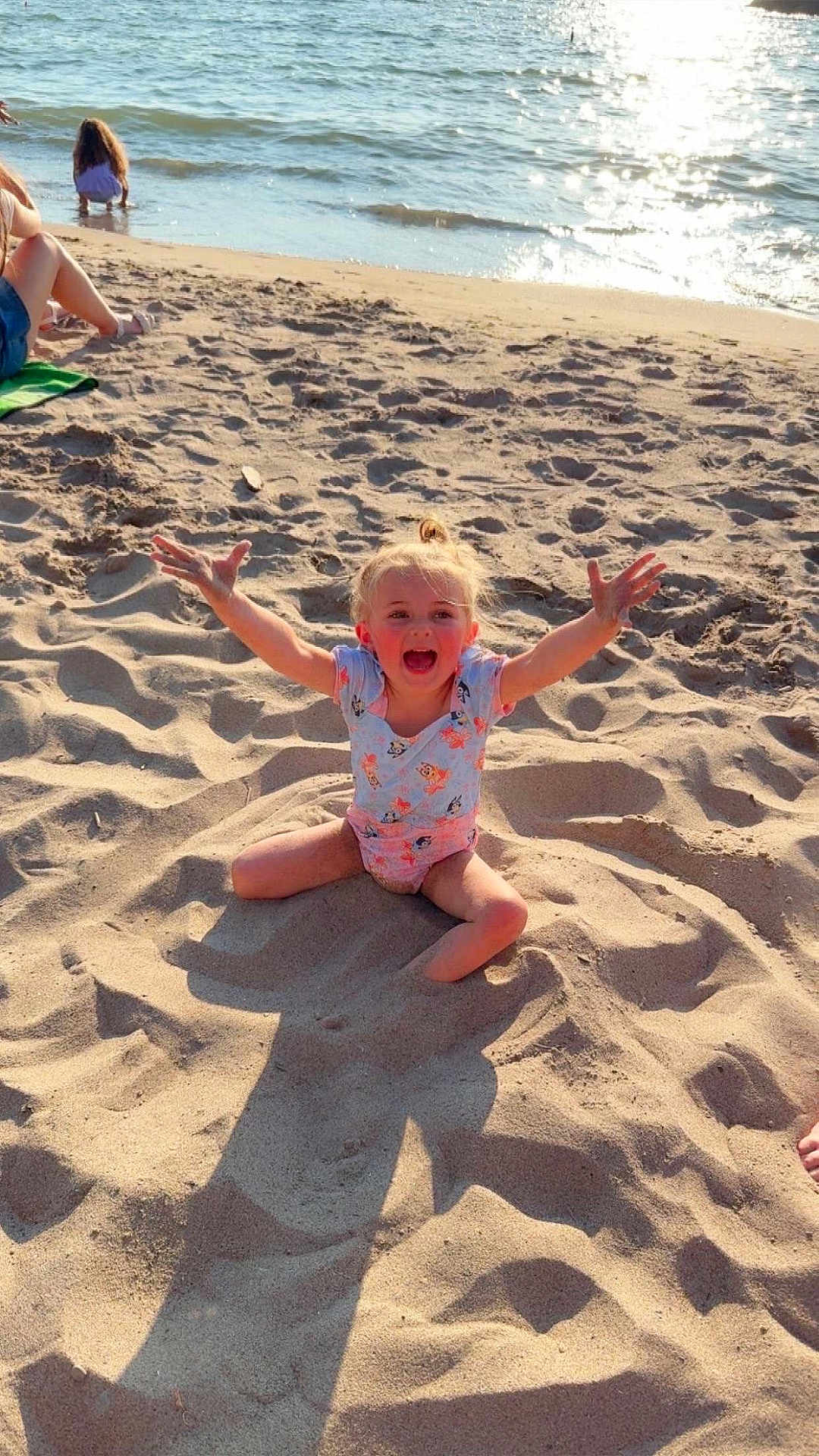 Ivy Mae Bell is registered to the contest to win money with this photo: child, beach, sand, water, sunlight, happy, smiling, summer, outdoor, play, ocean, shore, casual_clothing, blond_hair, sunshine, fun, vacation, relaxation, person, nature