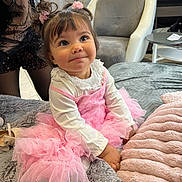 Isis a rejoint le concours — aidez-le/la à gagner de superbes lots ! toddler, child, pink_tutu, dress, curly_hair, pigtails, hair_accessories, smiling, indoor, blanket, soft_toy, chair, window, cozy, cute, happy, person, fashion, portrait, home