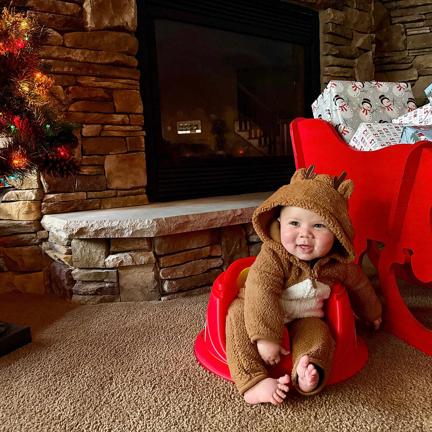 Nickeil joined the competition — help win amazing prizes! baby, carpet, child, christmas_sleigh, christmas_tree, cozy, cute, festive, fireplace, happy, holiday_decor, holiday_lights, indoors, infant, red_baby_seat, reindeer_onesie, seasonal, smiling, stone_wall, wrapped_gifts