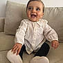 baby, black_leggings, child, couch, cozy, cute, expression, face, footwear, furniture, hand, happy, human, indoors, portrait, sitting, skin, smiling, white_blouse, young_child