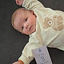 Marius participe au concours pour gagner de l'argent avec cette photo : baby, infant, child, teddy_bear, clothing, card, laying_down, cute, portrait, face, hand, cozy, soft, looking, curious, cream_color, dark_background, newborn, three_months, indoors