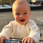 Raphaël a rejoint le concours — aidez-le/la à gagner de superbes lots ! baby, child, smile, happy, shopping_cart, knitted_sweater, hand, face, outdoor, parking_lot, daylight, person, clothing, blond_hair, cute, closeup, portrait, retail, infant, holding