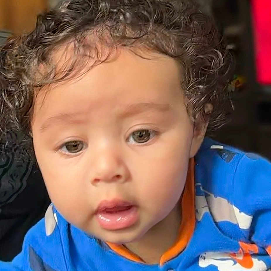 Gregory is registered to the contest to win money with this photo: baby, blue_clothing, casual, child, closeup, cozy, curiosity, curly_hair, cute, expression, eyes, face, indoor, infant, mouth, person, portrait, skin, toddler, young_child