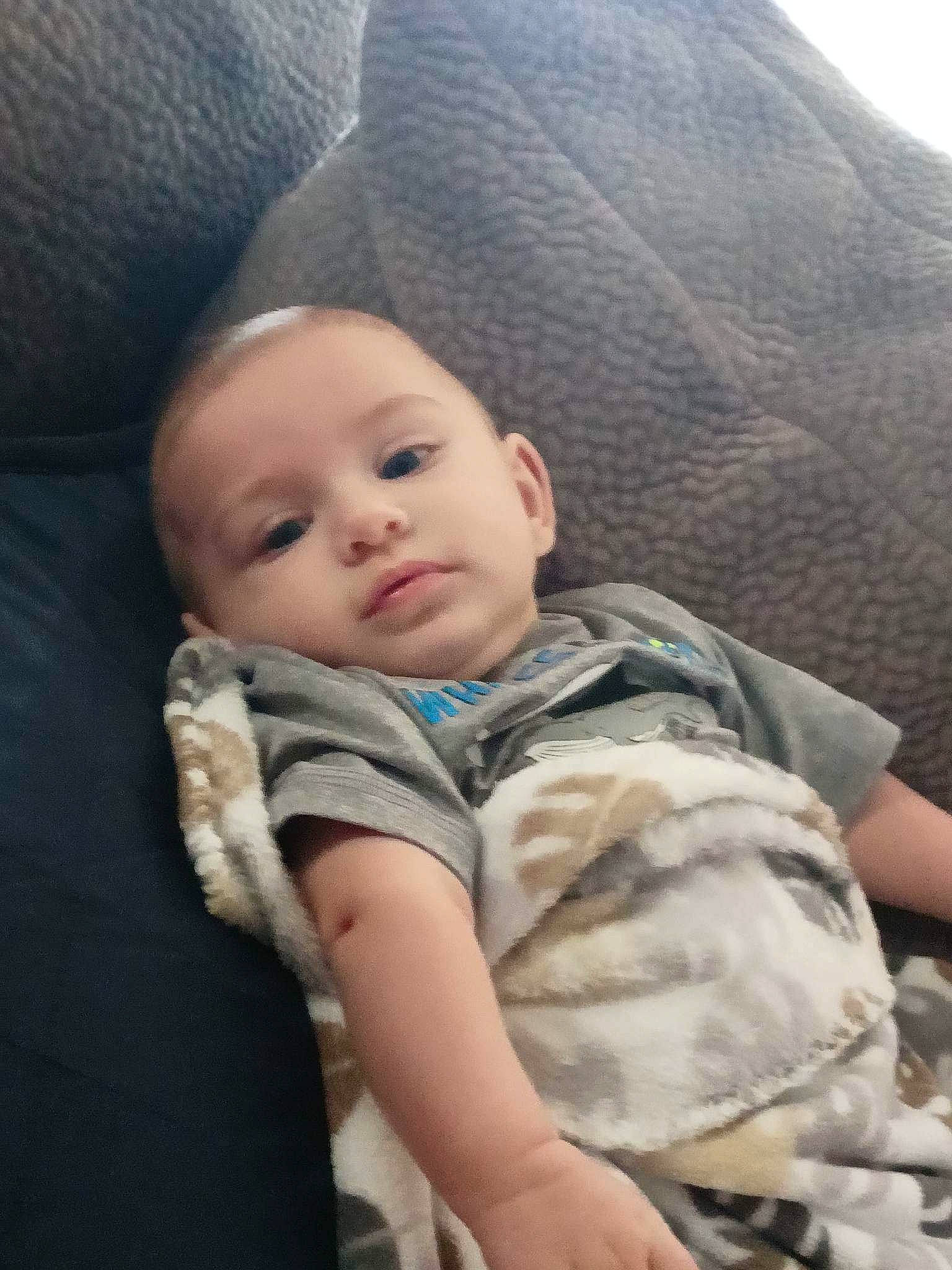 Chase is registered to the contest to win money with this photo: auto_part, baby, baby_products, baby_toddler_clothing, car_seat, cheek, child, comfort, eye, hat, linens, nose, person, sitting, skin, sleeve, textile, toddler, vacation