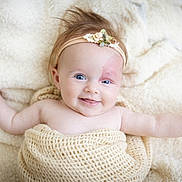 Lia participe au concours pour gagner de l'argent avec cette photo : baby, smiling, headband, flower, blanket, blue_eyes, infant, cute, soft_texture, cozy, lying_down, happy, skin, hand, portrait, child, warm, indoors, fluffy, closeup