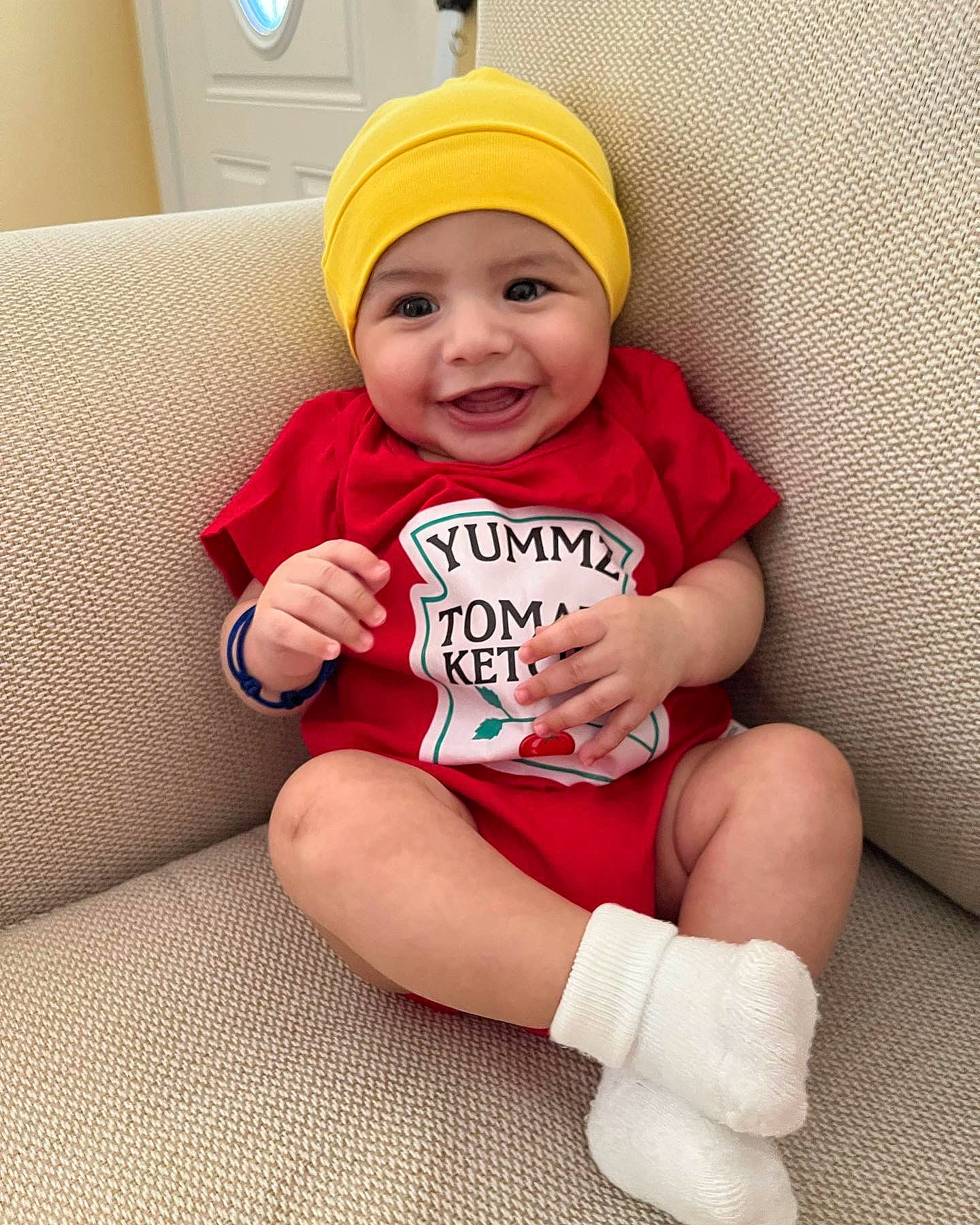 Moses is registered to the contest to win money with this photo: baby, baby_toddler_clothing, cap, child, comfort, eye, face, foot, happy, head, headgear, headwear, human_leg, joy, knee, person, sleeve, smile, sock, t_shirt