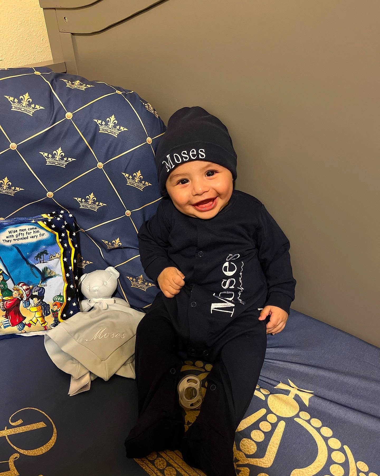 Moses is registered to the contest to win money with this photo: beanie, black, cap, carmine, child, comfort, event, flooring, fun, hat, headwear, hoodie, joy, linens, pattern, person, room, sitting, sleeve, smile