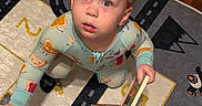 Grayson is registered to the contest to win money with this photo: toddler, child, curly_hair, blue_eyes, pajamas, book, play_mat, numbers, roads, indoor, carpet, floor, wood_floor, furniture, home, person, cute, curious, young_child, reading