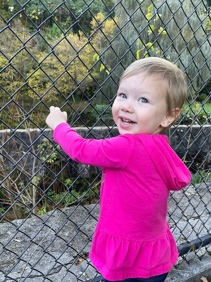 Kimberly is registered to the contest to win money with this photo: baby, baby_toddler_clothing, chain_link_fencing, child, fence, fun, grass, happy, home_fencing, joy, leisure, magenta, mesh, people_in_nature, person, pink, plant, recreation, sleeve, smile