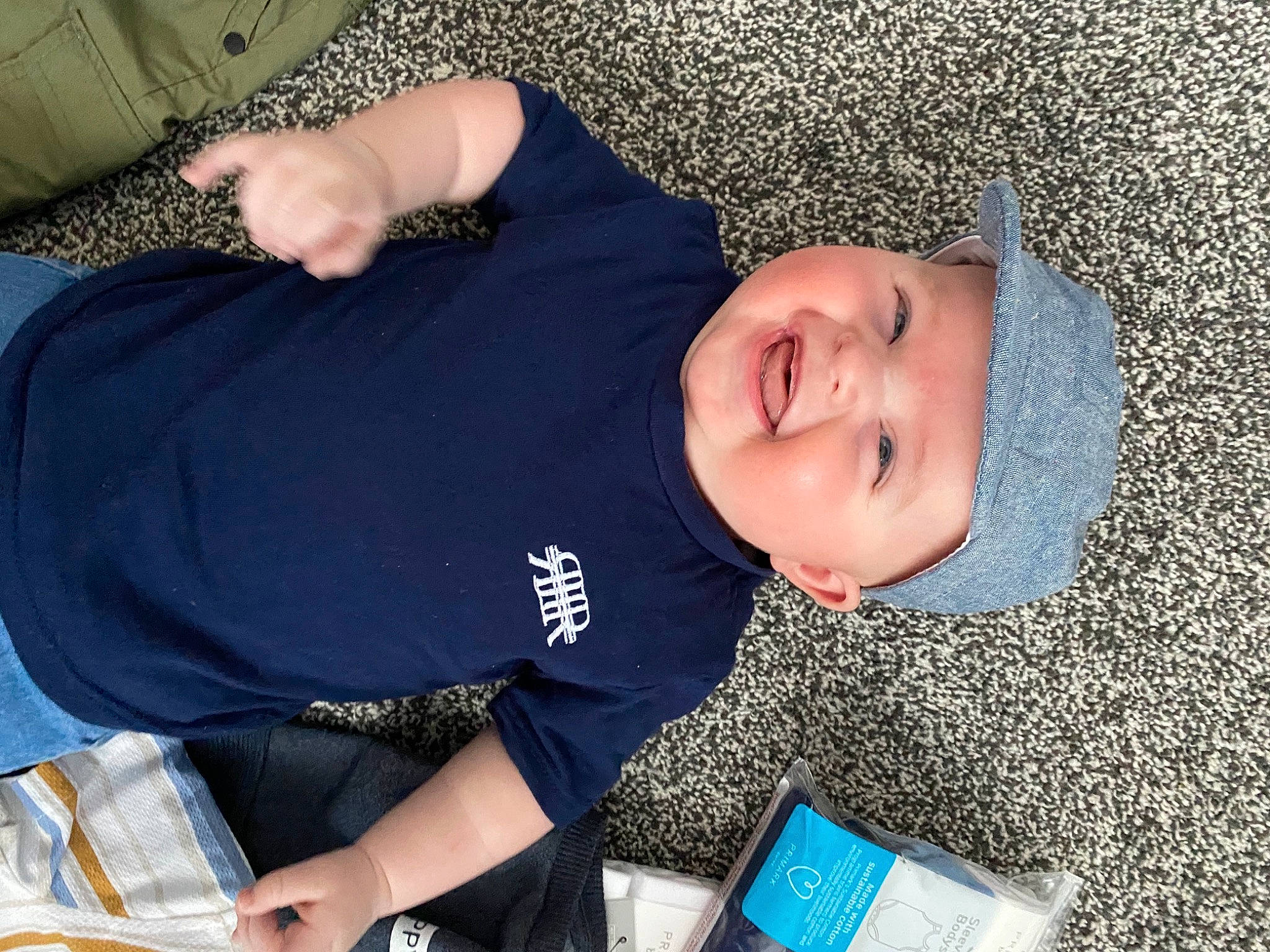 Zach is registered to the contest to win money with this photo: arm, child, comfort, elbow, electric_blue, fun, grass, happy, headwear, pattern, person, sitting, sleeve, smile, t_shirt, toddler