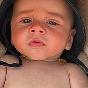 Elyias participe au concours pour gagner de l'argent avec cette photo : baby, infant, face, hat, black_hat, necklace, wooden_beads, skin, closeup, expression, curious, pout, human, child, portrait, young, headwear, indoors, soft_surface, person
