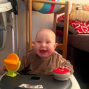 Taha participe au concours pour gagner de l'argent avec cette photo : baby, blanket, child, clothing, colorful, cushion, face, furniture, hand, happy, home, indoor, infant, person, play, seat, smiling, toy, walker, wooden_furniture