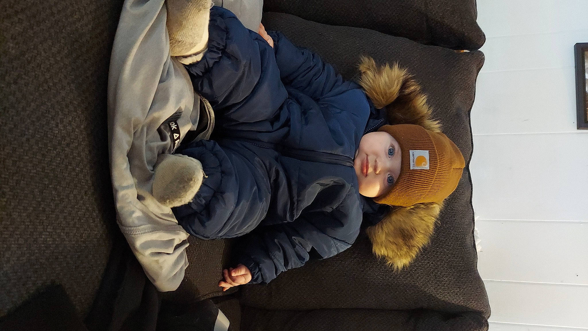 Jett is registered to the contest to win money with this photo: baby, bag, comfort, couch, fur, gesture, glove, grey, headgear, headwear, linens, nap, person, pillow, pocket, room, sitting, sleeve, stuffed_toy, toy