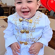 Cesar Mateo Morales joined the competition — help win amazing prizes! toddler, child, smiling, white_clothing, gold_embroidery, indoors, balloon, heart_shaped, happy, portrait, sitting, cute, formal_wear, baby, young_child, person, celebration, festive, bright, cheerful
