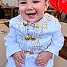 toddler, child, smiling, white_clothing, gold_embroidery, indoors, balloon, heart_shaped, happy, portrait, sitting, cute, formal_wear, baby, young_child, person, celebration, festive, bright, cheerful