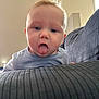 baby, blue_shirt, child, couch, cute, expression, face, furniture, head, home, indoor, infant, person, playful, portrait, skin, striped, tongue, tongue_out, young
