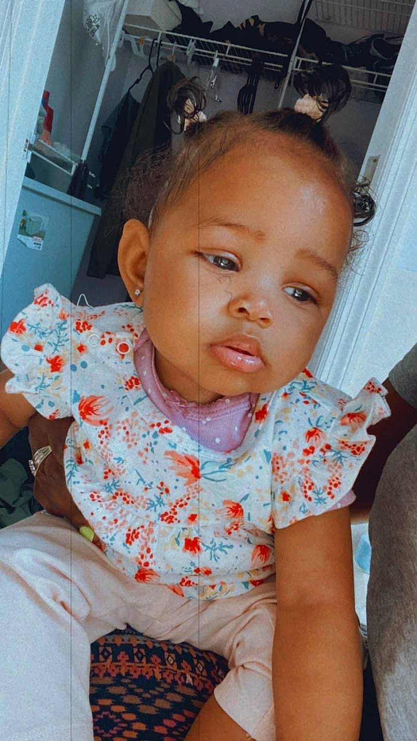 Ablessing Simpson is registered to the contest to win money with this photo: baby, baby_toddler_clothing, cheek, child, chin, curtain, dress, ear, eyelash, facial_expression, fun, hairstyle, happy, iris, nose, person, sitting, skin, sleeve, toddler