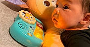 Zion joined the competition — help win amazing prizes! baby, bed, bedroom, black_clothing, child, closeup, colorful, curious, face, hand, indoor, infant, person, pillow, play, plush, resting, soft_toy, toy, young_child