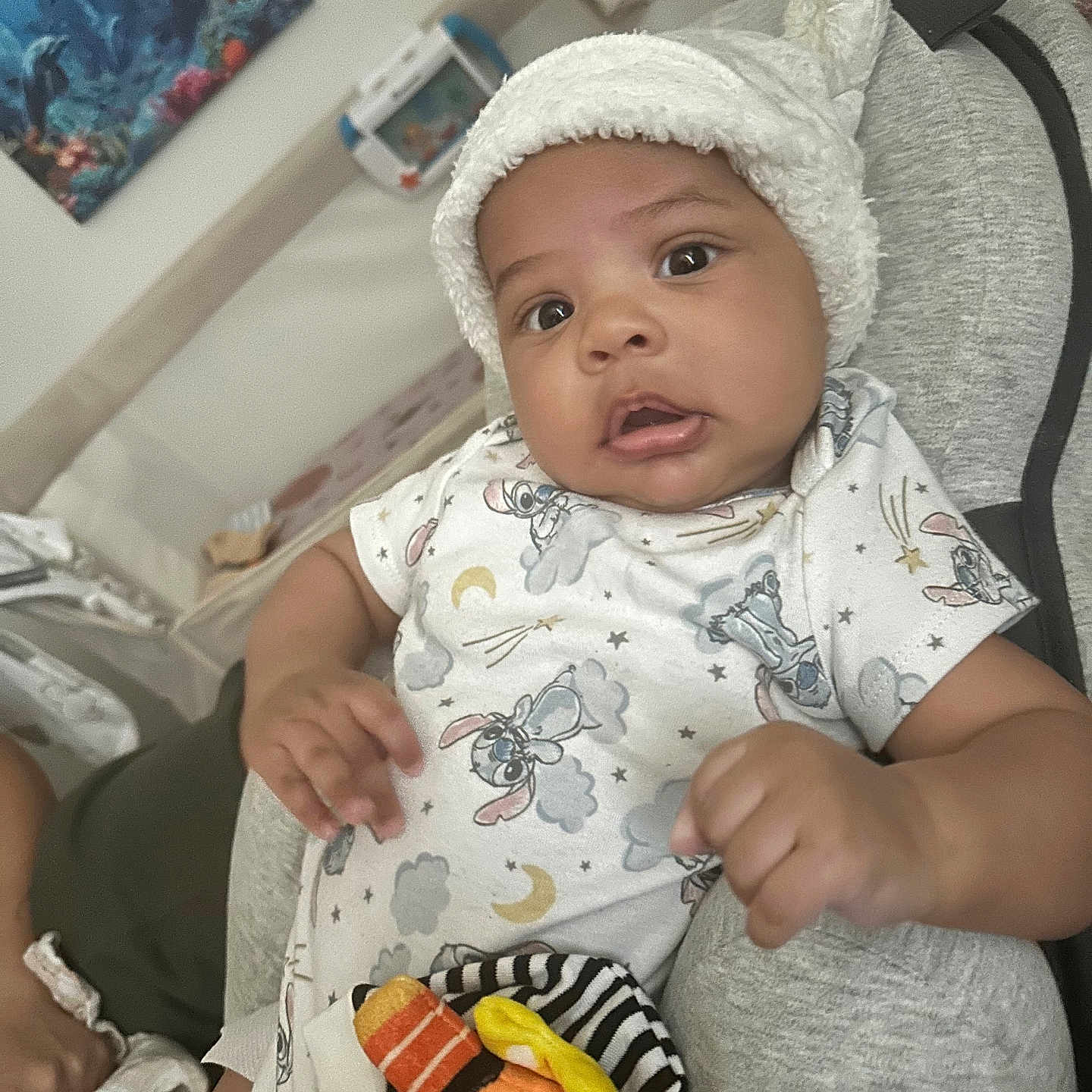 Zion joined the competition — help win amazing prizes! baby, infant, onesie, hat, plush_toy, cushion, indoor, portrait, child, cute, expression, clothing, furniture, person, face, headwear, home, relaxing, toy, comfortable