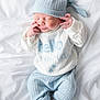 newborn, baby, sleeping, knitwear, blue_hat, blue_pants, white_sweater, blanket, soft_texture, infant, peaceful, cute, small_hands, small_feet, portrait, indoors, cozy, resting, child, sleep