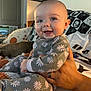 baby, child, smiling, onesie, floral_pattern, person, hand, indoor, happy, dog, blanket, seated, cozy, portrait, cute, face, skin, comfort, home, family