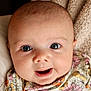 baby, blanket, blue_eyes, child, close_up, cute, expression, face, floral_clothing, happy, head, indoor, infant, newborn, person, portrait, skin, smile, soft_texture, young