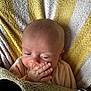 baby, infant, hand, face, blanket, striped, yellow, white, green, plush, soft, cozy, closeup, child, newborn, skin, expression, resting, indoors, comfort