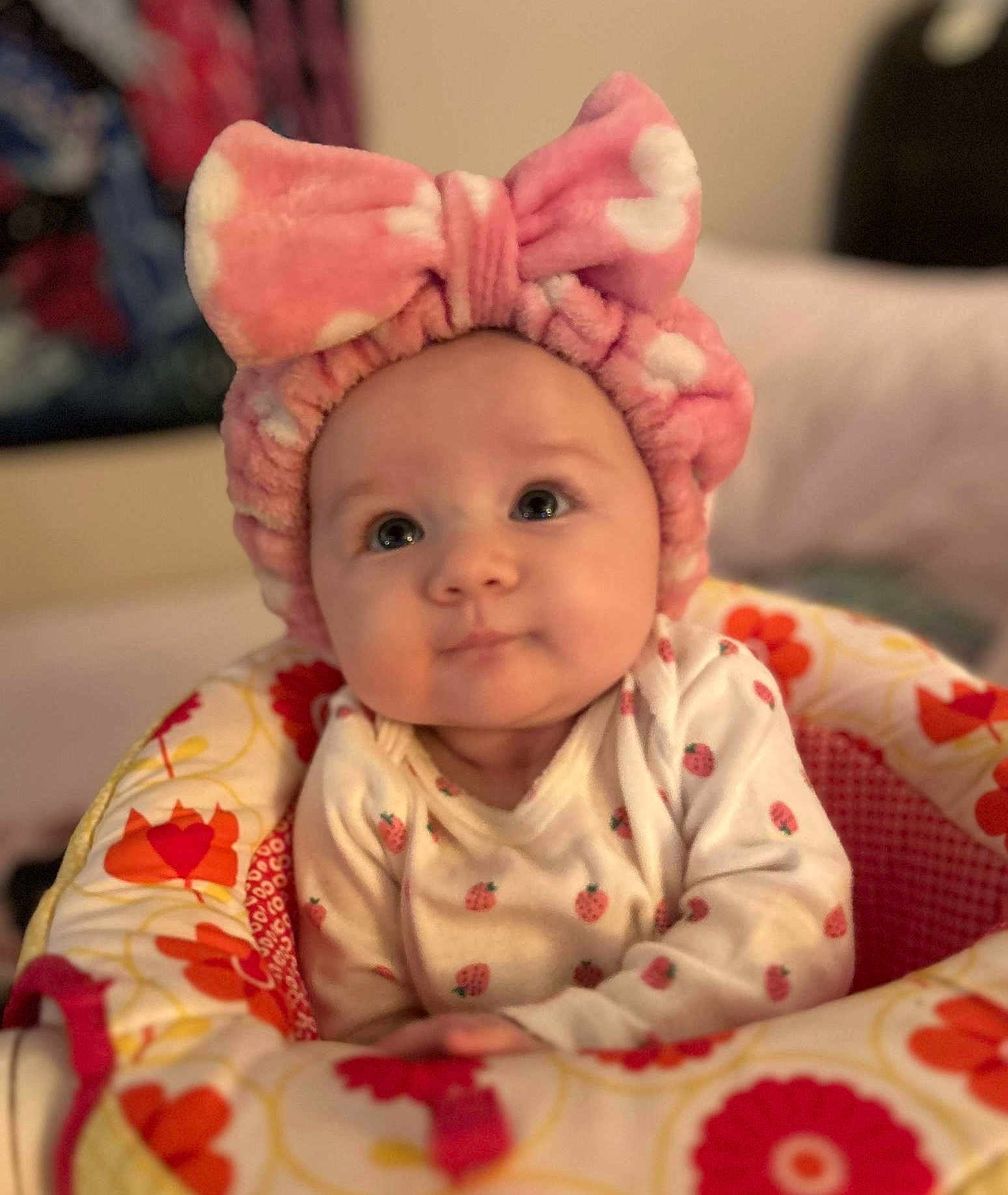 Haven is registered to the contest to win money with this photo: baby, infant, child, pink_headband, bow, fluffy, face, wide_eyes, curious, baby_seat, floral_pattern, clothing, cute, indoors, portrait, soft_lighting, hands, sitting, cozy, apparel