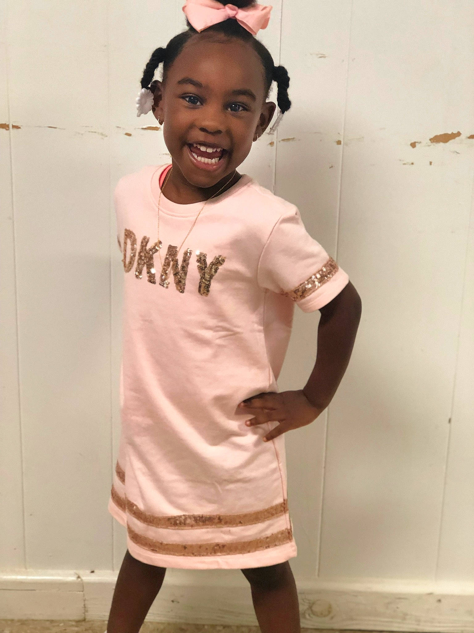 Keira is registered to the contest to win money with this photo: child, cool, ear, face, forehead, fun, gesture, head, joint, joy, neck, person, pink, room, shoulder, sleeve, smile, standing, t_shirt, toddler