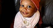 Tymir joined the competition — help win amazing prizes! baby, smiling, hat, bib, face, child, indoor, blanket, couch, leather, portrait, cute, happy, infant, young_child, clothing, headwear, sitting, expression, cozy