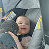 baby, child, car_seat, plush_toy, dragon, toy, smile, drool, infant, seatbelt, window_shade, happy, cute, indoors, person, face, hand, clothing, car_interior, soft_light