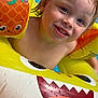child, toddler, smiling, wet_hair, inflatable, pool, water, yellow, float, shark_face, pineapple, summer, fun, play, happy, blue_eyes, skin, closeup, toy, outdoor