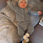 Noah participe au concours pour gagner de l'argent avec cette photo : baby, infant, child, hat, knit_hat, pom_poms, grey_clothing, onesie, couch, sofa, blanket, footwear, sneakers, floor, wood_floor, indoor, person, lying_down, cute, cozy