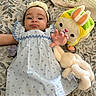 Abigail is registered to the contest to win money with this photo: baby, infant, child, dress, headband, pacifier, plush_toy, stuffed_animal, quilt, patterned_bedspread, reaching_hand, cute, indoors, lying_down, soft_toys, colorful_toy, bunny_ears, fabric, smiling, person