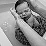 newborn, baby, infant, bath, hands, sleeping, black_and_white, water, towel, pattern, close_up, peaceful, skin, portrait, parent, care, gentle, rest, support, bathtub