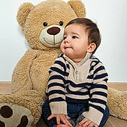 Maylone a rejoint le concours — aidez-le/la à gagner de superbes lots ! baby, toddler, teddy_bear, plush_toy, child, portrait, indoor, cute, striped_sweater, jeans, bare_feet, smile, soft_toy, wood_floor, sitting, face, fur, white_wall, cozy, playful