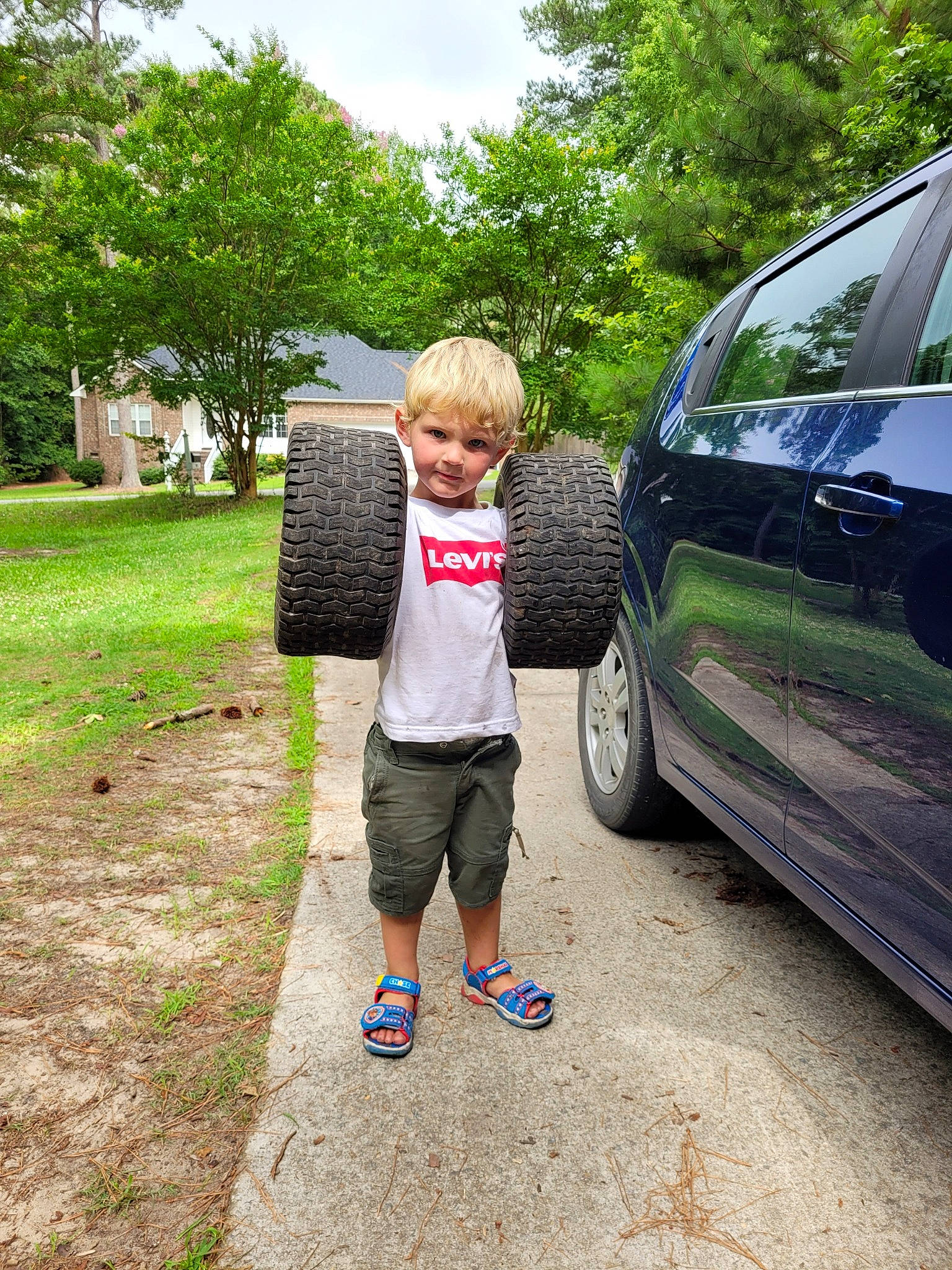 Brock is registered to the contest to win money with this photo: asphalt, automotive_design, automotive_exterior, automotive_tire, automotive_wheel_system, bumper, car, grass, landscape, leisure, motor_vehicle, person, plant, recreation, shorts, t_shirt, tire, toddler, tree, vehicle_door
