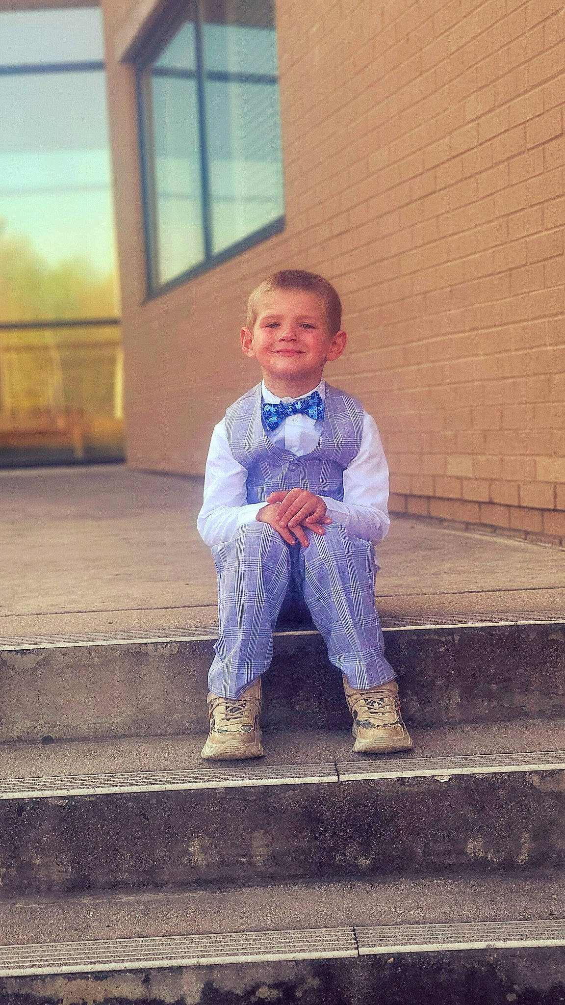 Brock is registered to the contest to win money with this photo: brick, denim, door, electric_blue, eye, face, flash_photography, flooring, formal_wear, fun, happy, joy, leisure, person, sitting, smile, stairs, symmetry, tints_and_shades, toddler