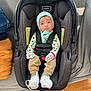 Uriel joined the competition — help win amazing prizes! baby, car_seat, infant, knit_hat, mittens, pants, socks, footwear, couch, pillow, blanket, wood_floor, indoor, person, child, face, seatbelt, clothing, cute, sitting
