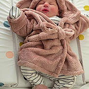 Ensley is registered to the contest to win money with this photo: baby, sleeping, robe, pink, hood, striped_clothing, footwear, mattress, polka_dots, soft_texture, infant, peaceful, cute, cozy, indoors, child, small, wrapped, lying_down, warm