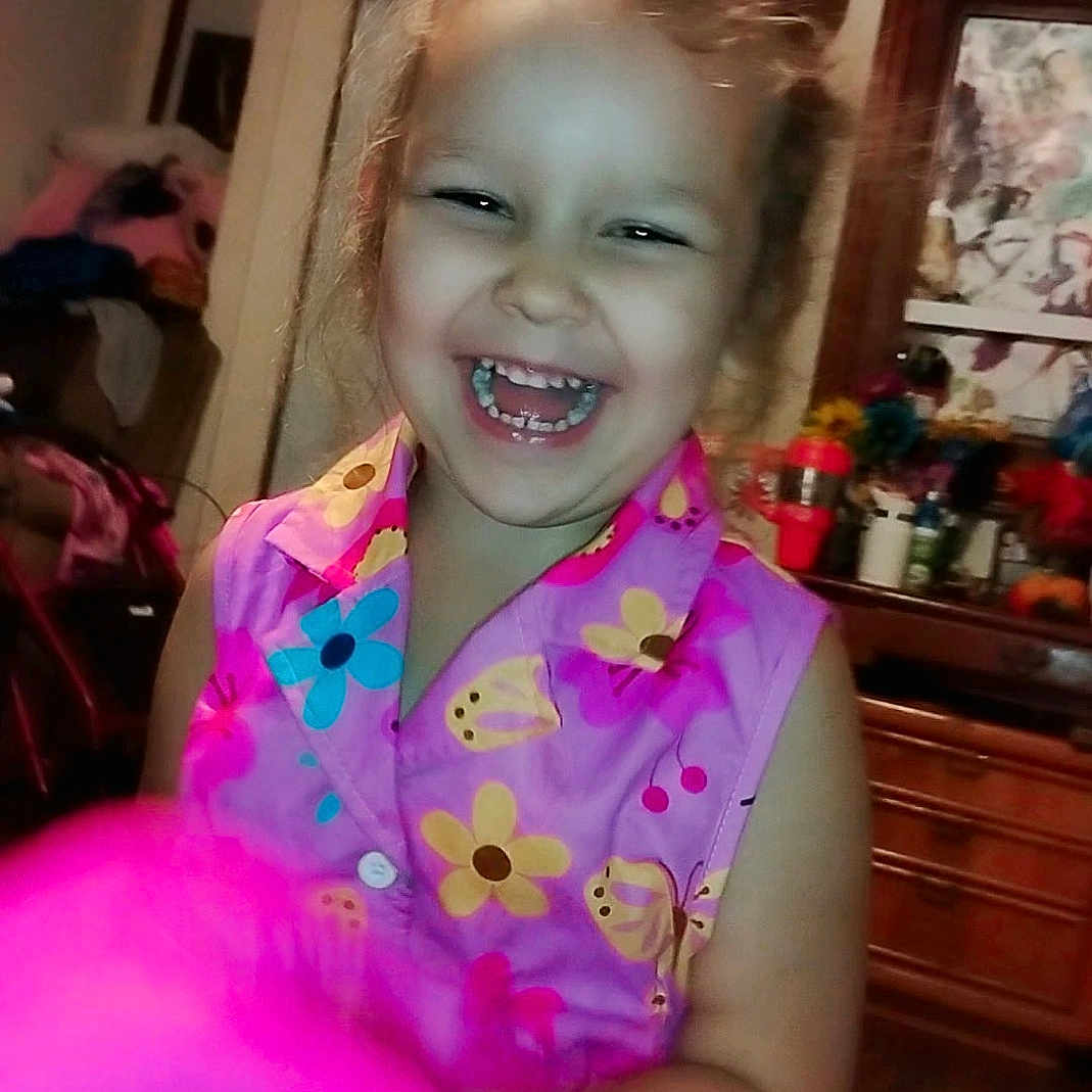 Ellianna is registered to the contest to win money with this photo: bow, cabinet, cheerful, child, clothing, decorations, dress, face, floral, furniture, girl, hair, happy, indoors, laugh, mirror, person, pink, room, smile