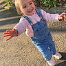 toddler, child, smiling, denim_overalls, pink_sweater, outdoor, sunlight, greenery, sidewalk, happy, person, young_child, casual_clothing, daylight, nature, portrait, cute, small_child, walking, joyful