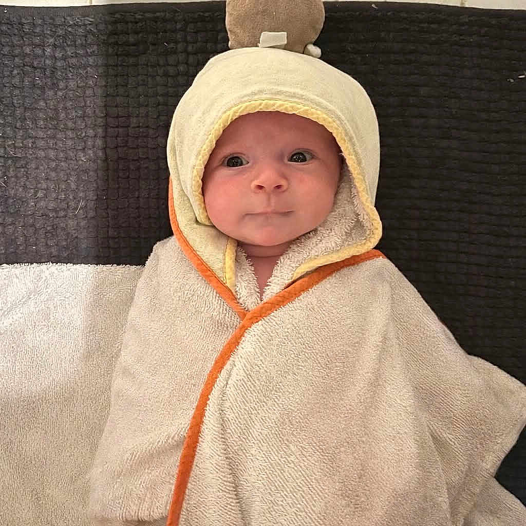 Anaya participe au concours pour gagner de l'argent avec cette photo : baby, blanket, child, cute, eyes, face, floor_tiles, hooded_towel, indoors, infant, laying_down, looking_at_camera, orange_trim, plush_toy, portrait, smile, soft, texture, towel, wrapped